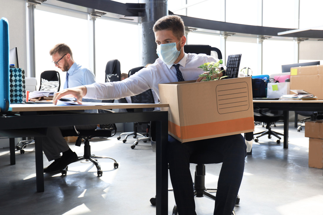 Employee being terminated during pandemic packing up belongings at desk